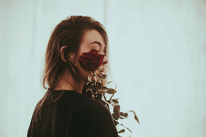 Portrait photography of a girl holding a rose by her face. Self portrait photography tips.
