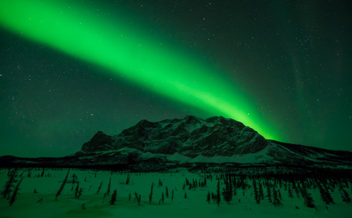 Photo of the northern lights over a mountainous landscape. Winter photography.
