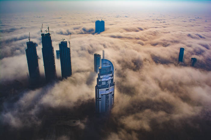 An aerial view of tall skyscrapers bursting through clouds - cloudy day photography 
